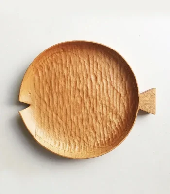 A round wooden plate made of cherry wood, shaped like a fish