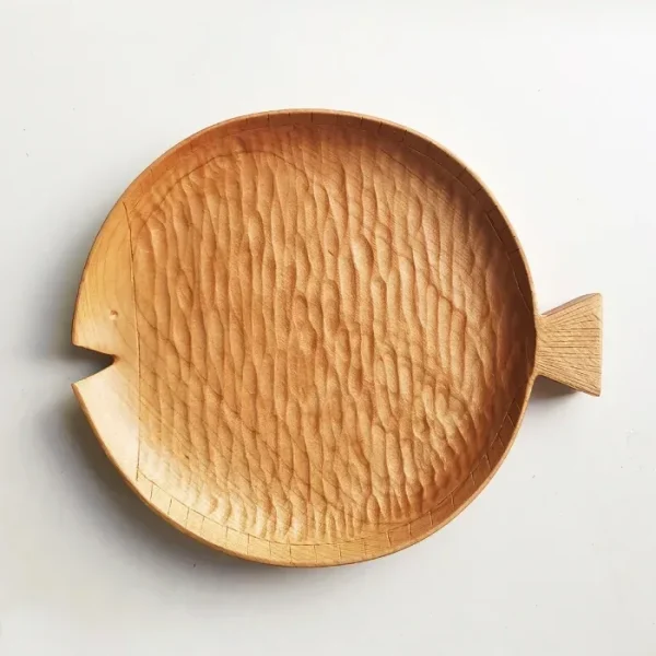 A round wooden plate made of cherry wood, shaped like a fish