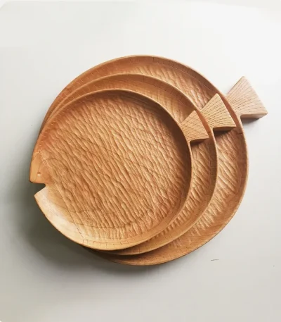 A set of three round cherry wood plates, shaped like fish