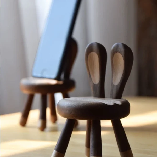 A wooden phone stand with bunny ears, perfect as a gift