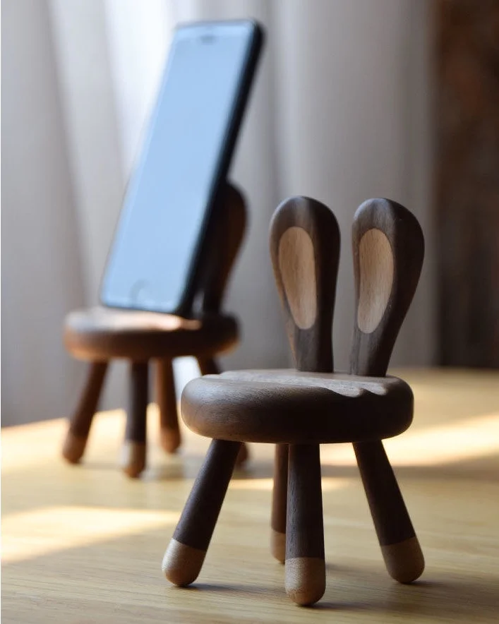 A wooden phone stand with bunny ears, perfect as a gift