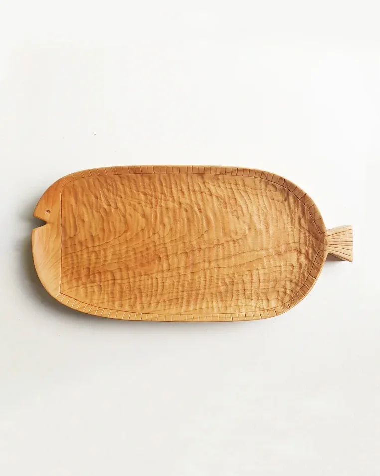 A long wooden plate made of cherry wood, shaped like a fish